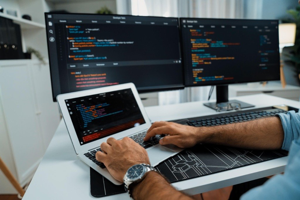 Developer coding at a multi-monitor setup